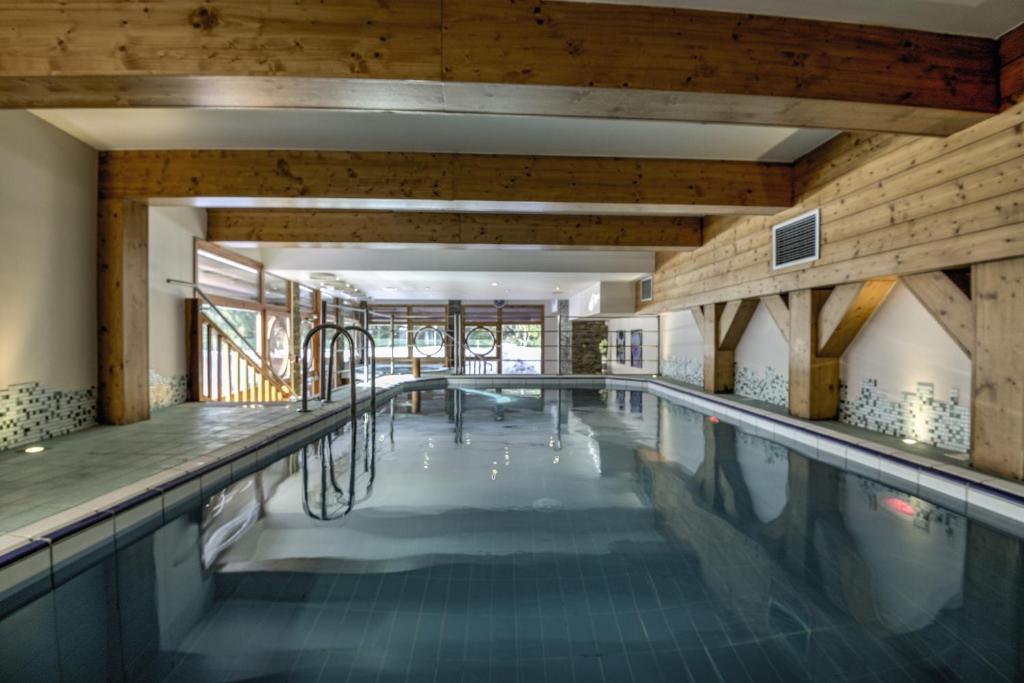 une grande piscine avec un plafond en bois et une grande fenêtre dans l'établissement Belambra Clubs Arc 1800 - Hôtel Du Golf, à Arc 1800