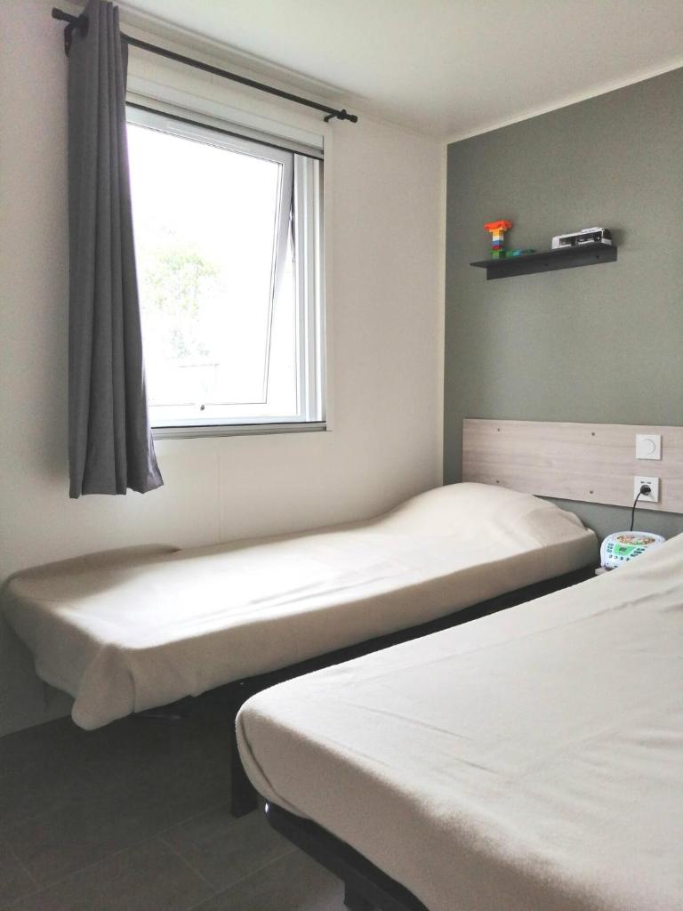 une chambre avec deux lits et une fenêtre dans l'établissement Mobil Home Le Rimbaud - 4/6 pers - 2 ch - 2 sdb, à Saint-Jean-de-Monts