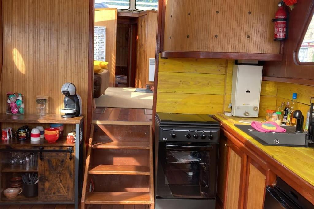une cuisine avec des armoires en bois et un four à plaques de cuisson dans l'établissement L'Amazone - bateau à quai sur le canal de bourgogne, à Tanlay