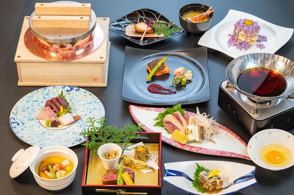 une table avec des assiettes et des bols de nourriture dans l'établissement Ishinoya Izunagaoka - TKP Hotels & Resorts, à Izunokuni