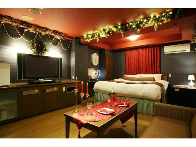 - une chambre avec un lit et une table avec une télévision dans l'établissement Hotel Chapel Christmas Narita -Adult Only, à Narita