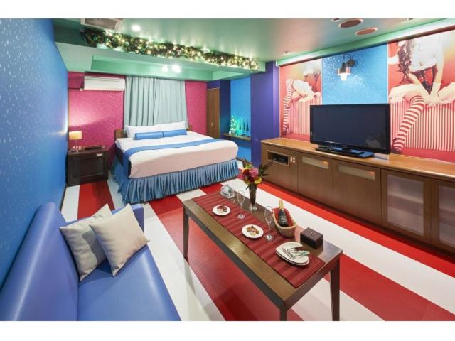 une chambre avec un lit, une télévision et un canapé dans l'établissement Hotel Chapel Christmas Narita -Adult Only, à Narita