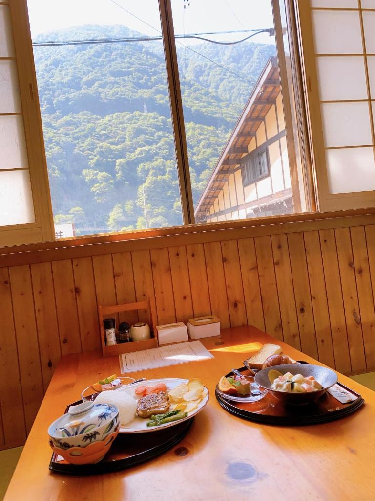 deux assiettes de nourriture sur une table dans une pièce avec une fenêtre dans l'établissement Hakuunsou, à Takayama