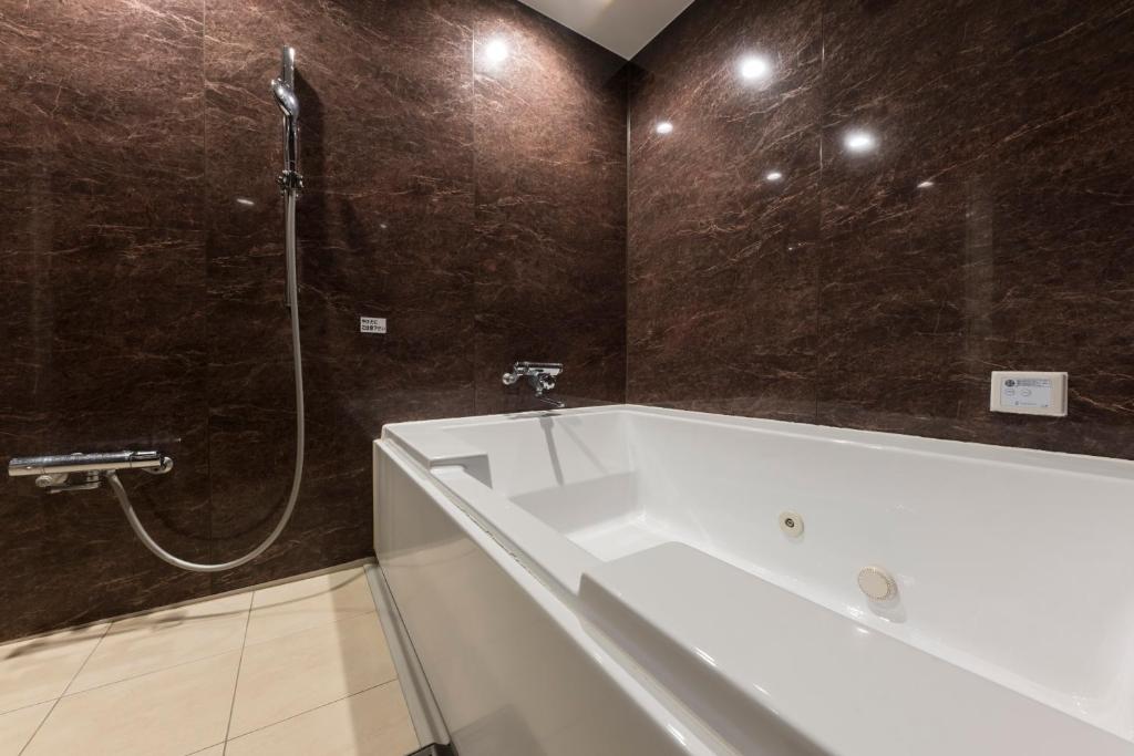 une salle de bain avec une baignoire blanche et une douche dans l'établissement ホテルＫＩＮＧＤＡＭ, à Osaka