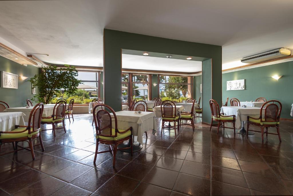 une salle à manger avec des tables et des chaises blanches dans l'établissement Hotel Kristina, à Imperia