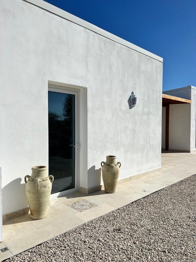 deux grands vases posés à l'extérieur d'un bâtiment blanc dans l'établissement NOTO country farm house -Tenuta Alessandra, à Noto