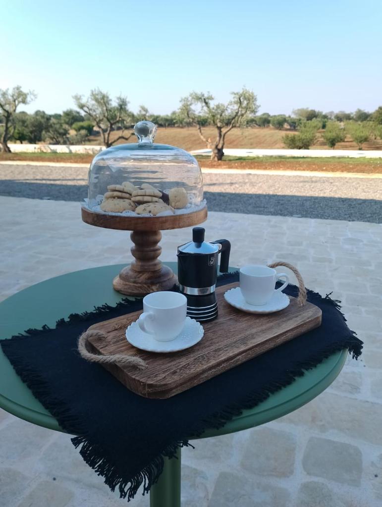 - une table avec un plateau de nourriture et de tasses ainsi qu'un plat en verre dans l'établissement Trulli Enjoy, à Noci
