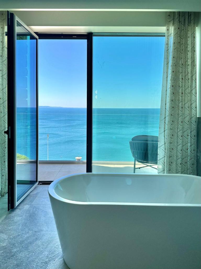 La salle de bains est pourvue d'une baignoire et offre une vue sur l'océan. dans l'établissement Maximilian Suites, à Trieste