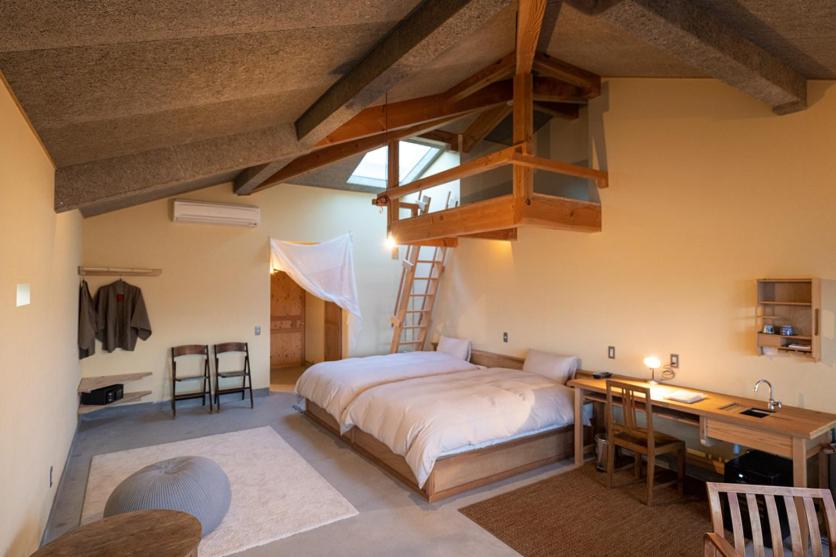 - une chambre avec un lit, un bureau et une mezzanine dans l'établissement Nisainoyuyado Asahiya, à Beppu