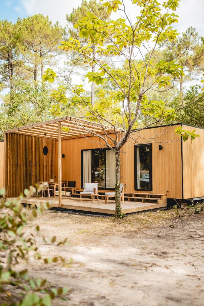 une petite maison en bois avec un arbre devant dans l'établissement Les Maritimes, à Seignosse