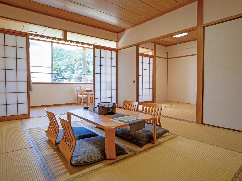 une pièce avec une table, des chaises et une fenêtre dans l'établissement 真田昌幸-幸村父子の隠れ宿 紀伊見荘, à Hashimoto
