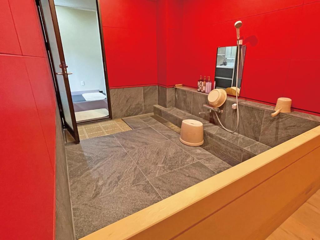 La salle de bains est pourvue d'une douche et d'un mur rouge. dans l'établissement 真田昌幸-幸村父子の隠れ宿 紀伊見荘, à Hashimoto