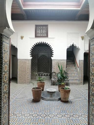 une cour avec des plantes en pot dans un bâtiment dans l'établissement Riad Mtamer, Tetouan, à Tetouan