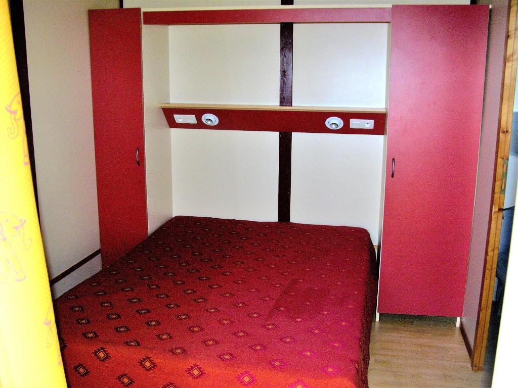 Cette petite chambre comprend un lit et un tapis rouge. dans l'établissement la Frégière Chalets, à Clairvaux-dʼAveyron 37 autres photos