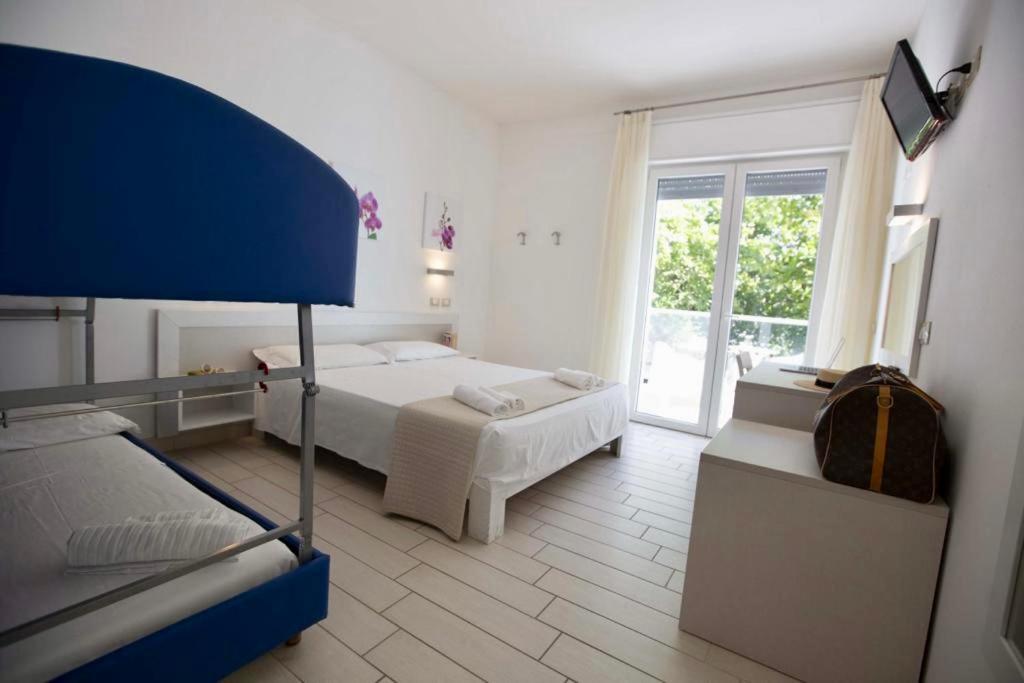 une chambre avec deux lits et une grande fenêtre dans l'établissement Hotel Elite, à Cervia