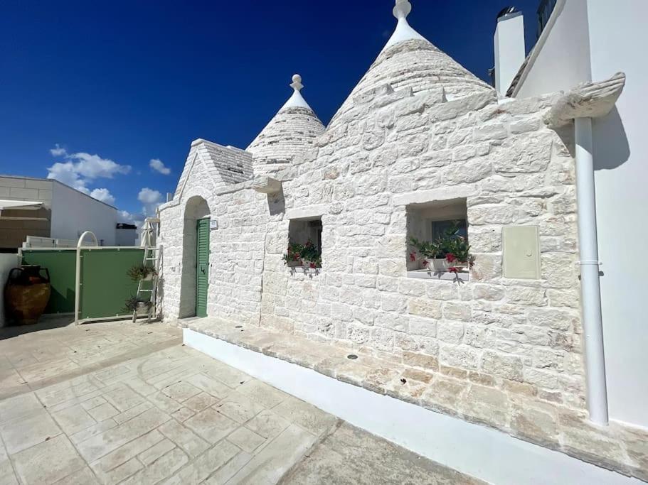 un bâtiment en pierre blanche avec deux fenêtres et des fleurs dans l'établissement SUITE - Trullo Relax sul Monte, à Cisternino