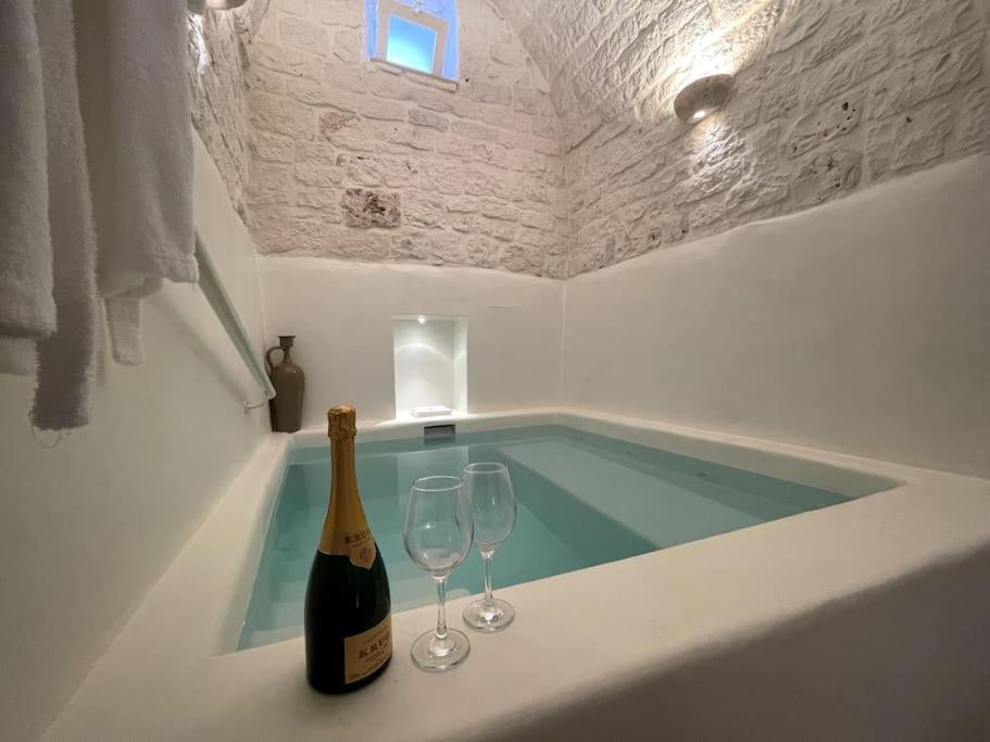 - une bouteille de champagne et 2 verres à vin dans la baignoire dans l'établissement SUITE - Trullo Relax sul Monte, à Cisternino