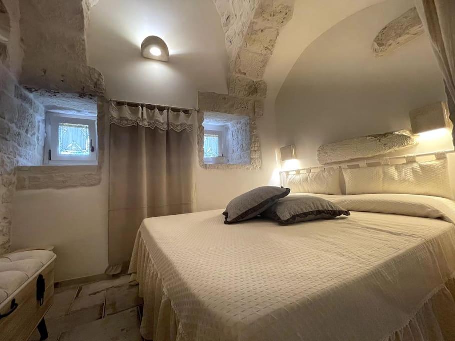 - une chambre avec un lit blanc et 2 fenêtres dans l'établissement SUITE - Trullo Relax sul Monte, à Cisternino