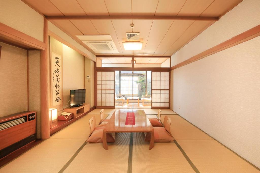 une pièce avec une table, des chaises et une télévision dans l'établissement Hotel Pony Onsen, à Towada