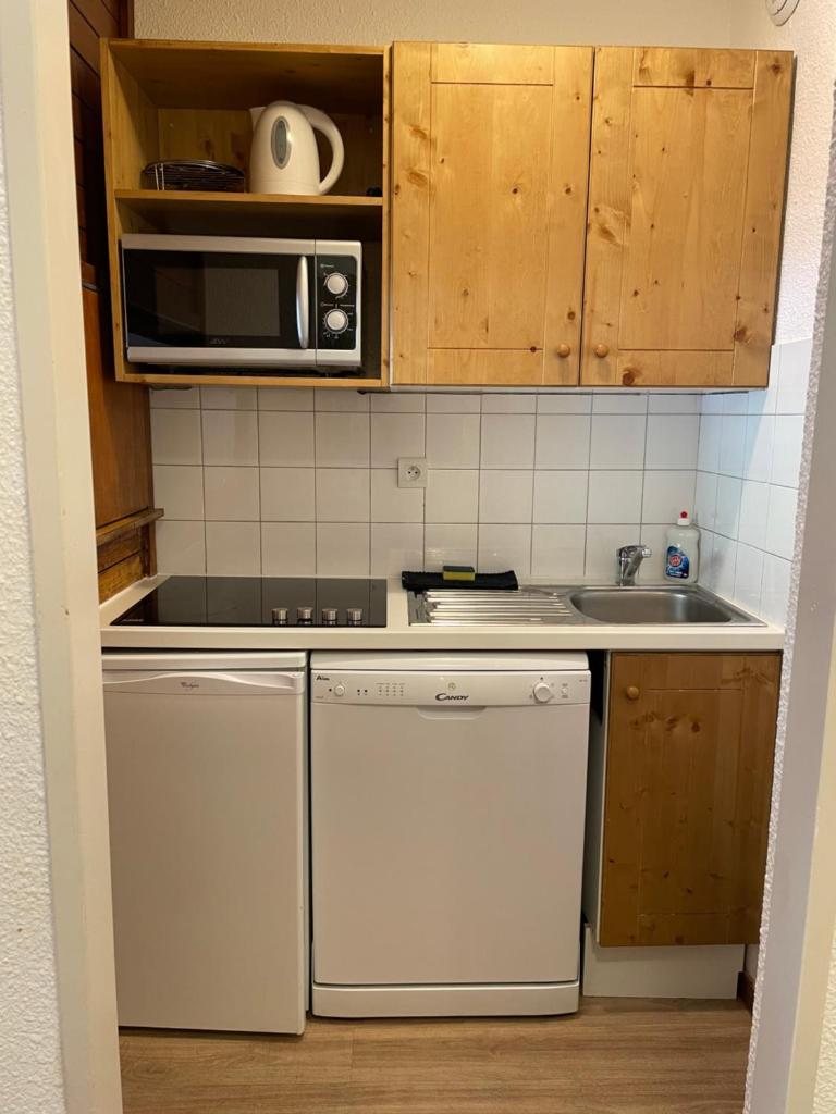 une petite cuisine avec un évier et un micro-ondes dans l'établissement Rond point des pistes 21m pour 4 internet fibre smart TV, à Tignes