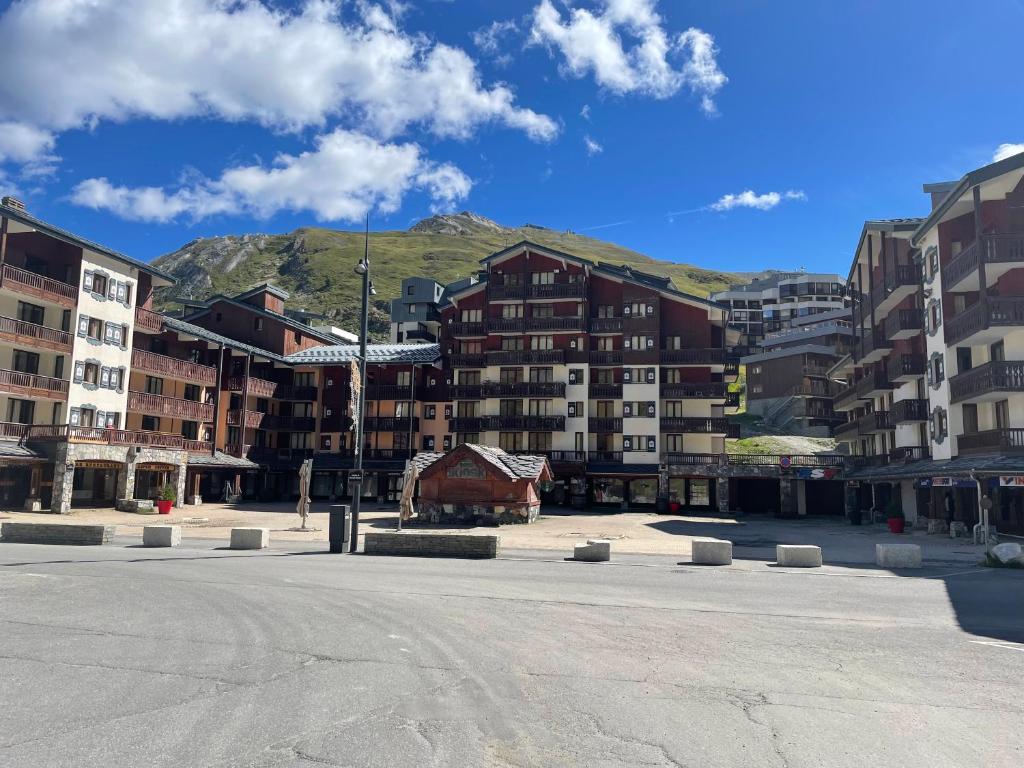 un groupe de bâtiments avec une montagne en arrière-plan dans l'établissement Rond point des pistes 21m pour 4 internet fibre smart TV, à Tignes