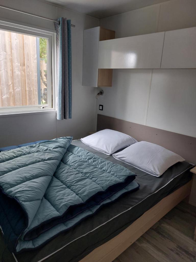 un grand lit dans une chambre avec une fenêtre dans l'établissement Mobil-home "La Perle Bleue" Ouistreham, à Ouistreham