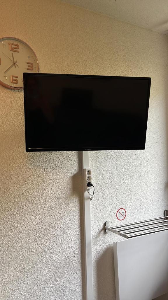 une télévision à écran plat sur un mur à côté d'une horloge dans l'établissement Ski Piau engaly 50 m des pistes de ski et du cœur de station, à Aragnouet