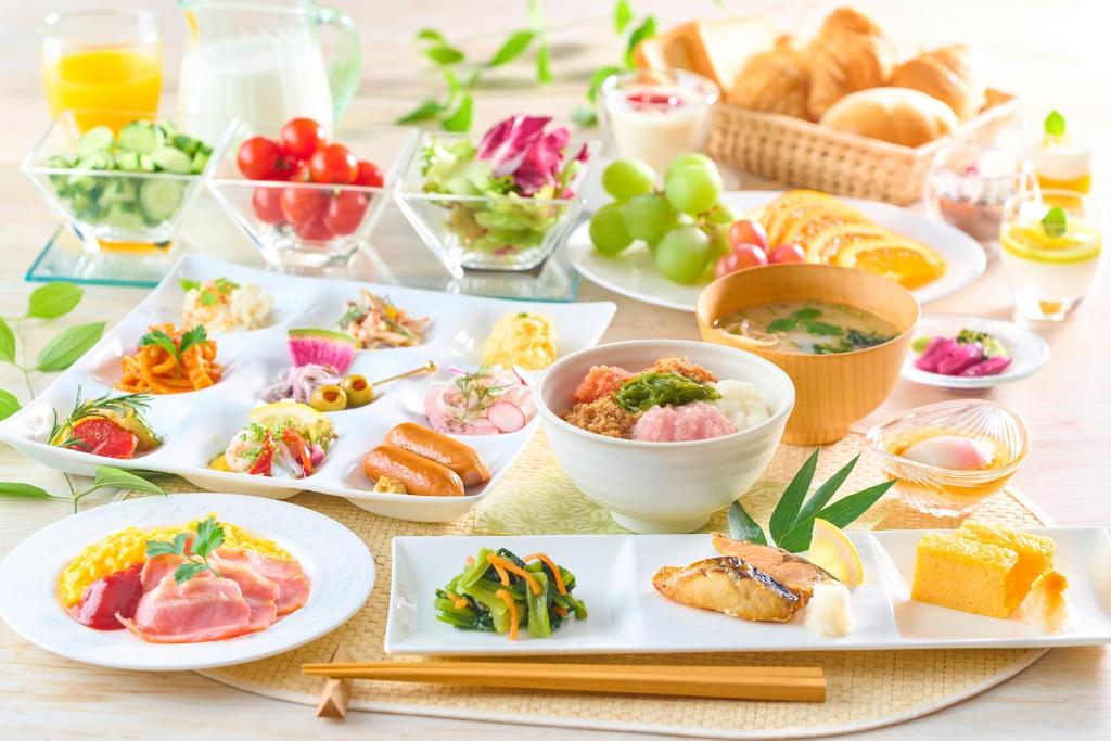 une table avec des assiettes et des bols de nourriture dans l'établissement Ooedo Onsen Monogatari Hotel Shinko, à Fuefuki