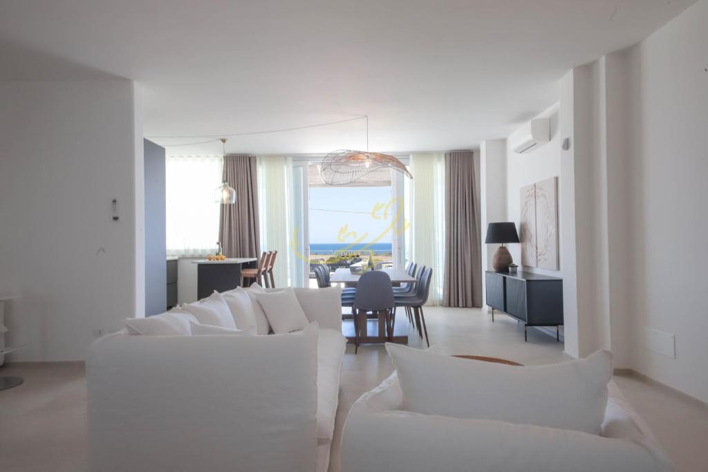 - un salon avec des canapés blancs et une salle à manger dans l'établissement TD Villa Grecale Modern Luxury Villa with Sea View, à Capitolo