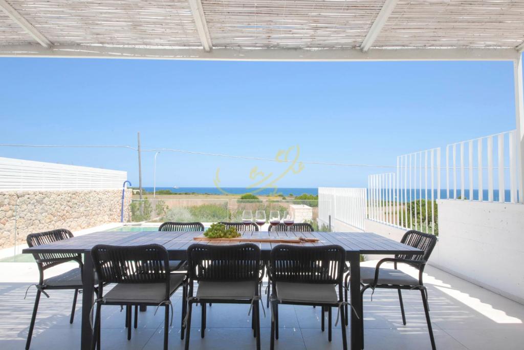 - une table à manger et des chaises sur une terrasse donnant sur l'océan dans l'établissement TD Villa Grecale Modern Luxury Villa with Sea View, à Capitolo