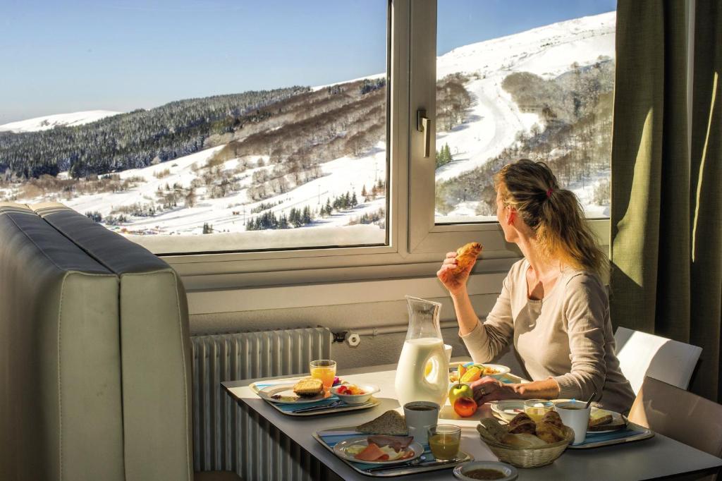une femme assise à une table qui mange de la nourriture dans un train dans l'établissement Belambra Clubs Superbesse - Le Chambourguet, à Super-Besse