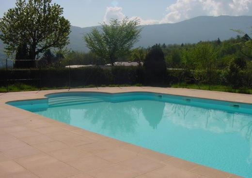 une grande piscine bleue dans une cour dans l'établissement L'Azuré, à Novalaise