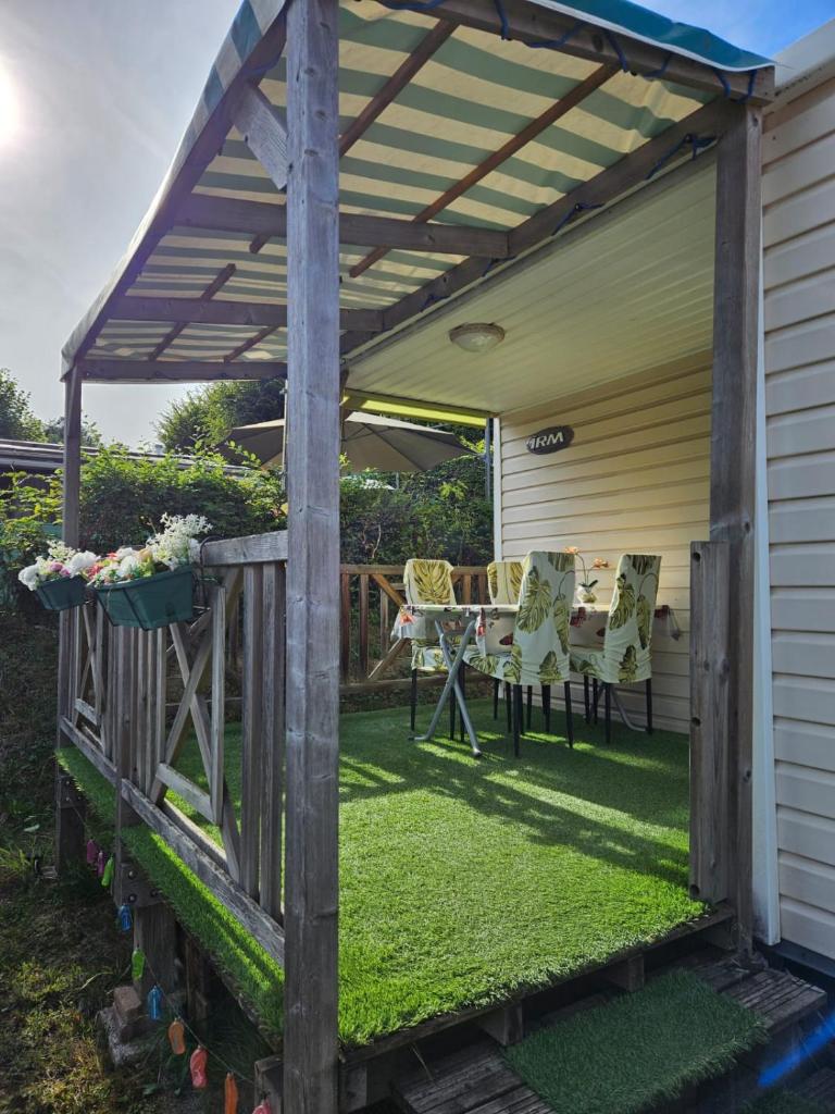 une pergola en bois avec une table et des chaises dans une cour dans l'établissement L'Azuré, à Novalaise