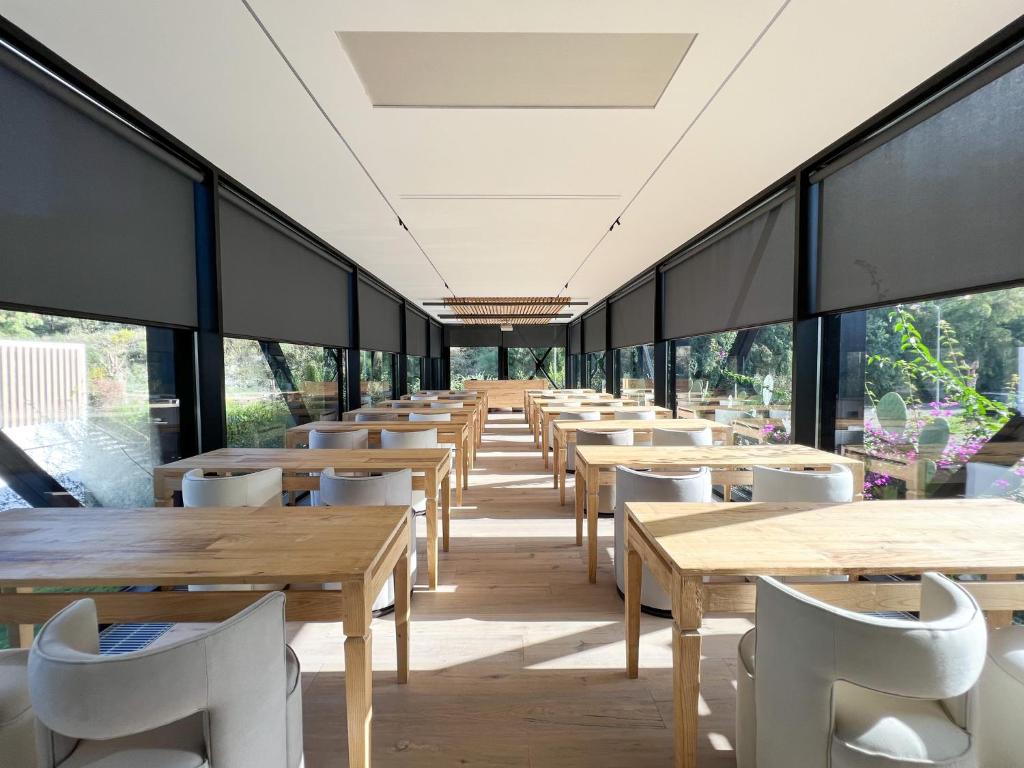 - une rangée de tables et de chaises dans un restaurant doté de grandes fenêtres dans l'établissement Praia Art Resort - Small Luxury Hotels of the world, à Le Castella