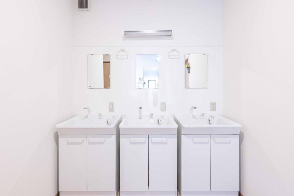 une salle de bain blanche avec deux lavabos et un miroir dans l'établissement add-Hostel Uji Cha-gan-ju-tei, à Uji 37 autres photos