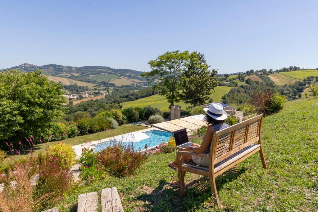 une femme assise sur un banc avec un ordinateur portable dans l'établissement Grano - Casa Bella Vista, à Force