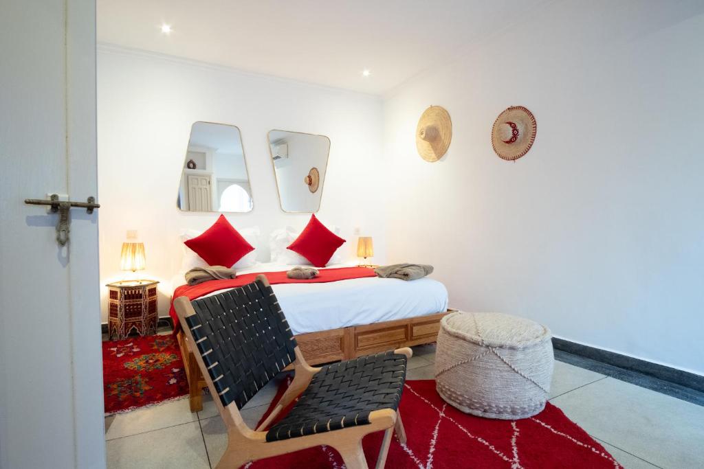 - une chambre avec un lit doté d'oreillers rouges et d'une chaise dans l'établissement Riad Bibazia, à Marrakech