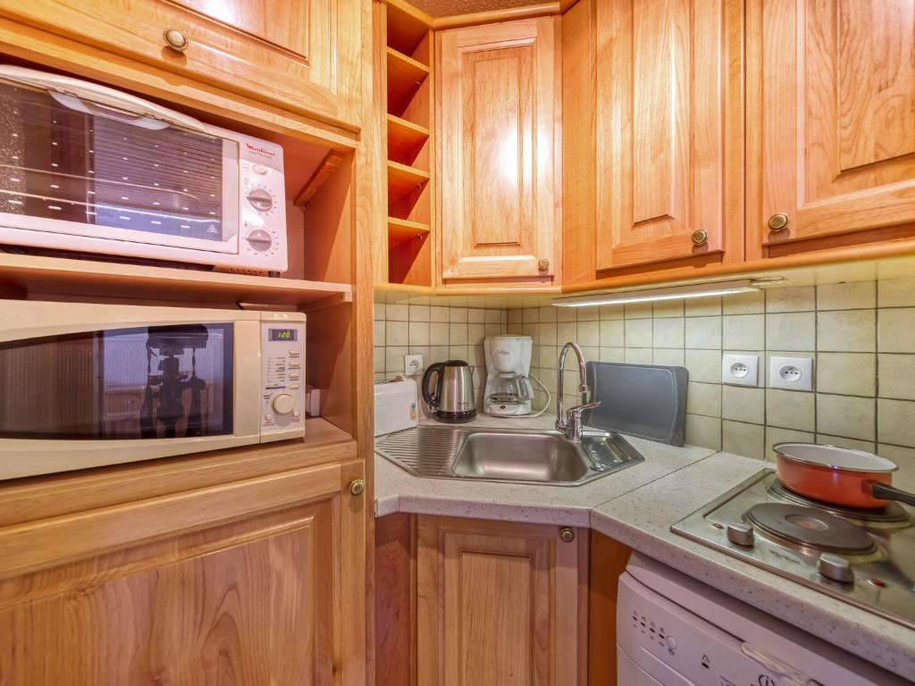 La cuisine est équipée de placards en bois, d'un évier et d'un four micro-ondes. dans l'établissement Apartment Pegase Phenix-74 by Interhome, au Corbier