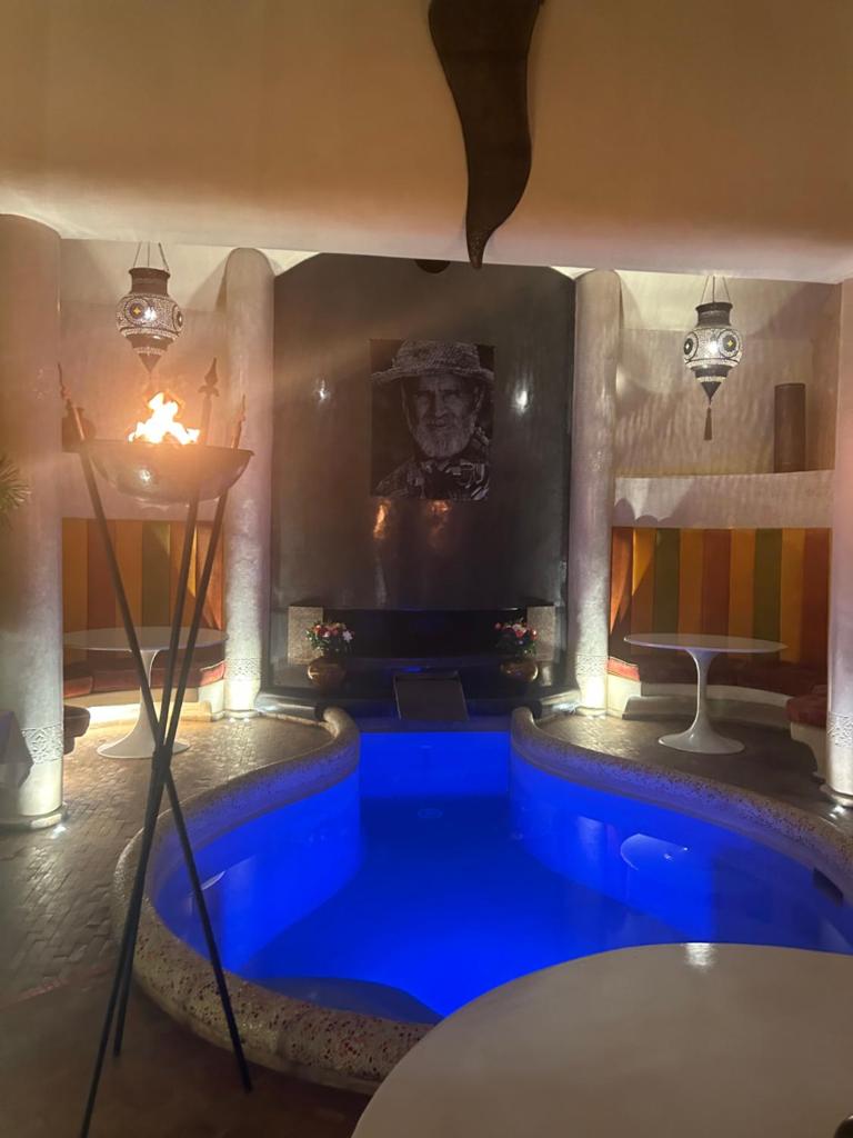 une chambre avec une piscine bleue en face d'une cheminée dans l'établissement MAISON MK Adults ONLY - Music Riad, à Marrakech