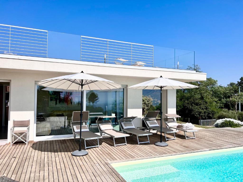 un patio avec chaises et parasols à côté d'une piscine dans l'établissement Villa Olympia Pool Sea View Mountains Lake Nature Sleeps 8 Air Conditioning Wi-Fi, à Corsanico-Bargecchia