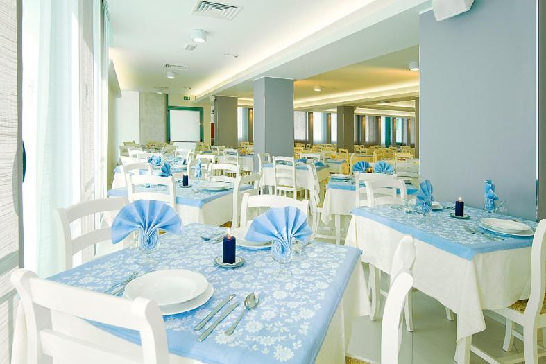 une salle à manger avec des tables et des chaises bleues et blanches dans l'établissement Hotel Bolivar, à Lido di Jesolo