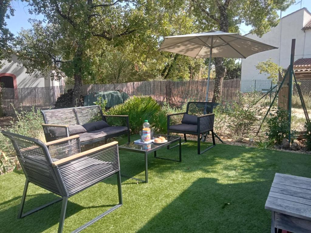 un patio avec des chaises, une table et un parasol dans l'établissement GITE LES MINOUX, à Saint-Julien-de-Cassagnas