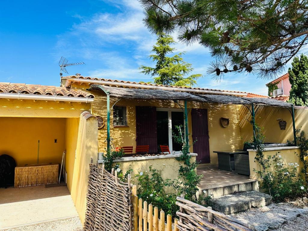 une maison jaune avec une clôture en bois devant elle dans l'établissement La Pitchoune : Gîte aux pieds des Alpilles, à Mouriès