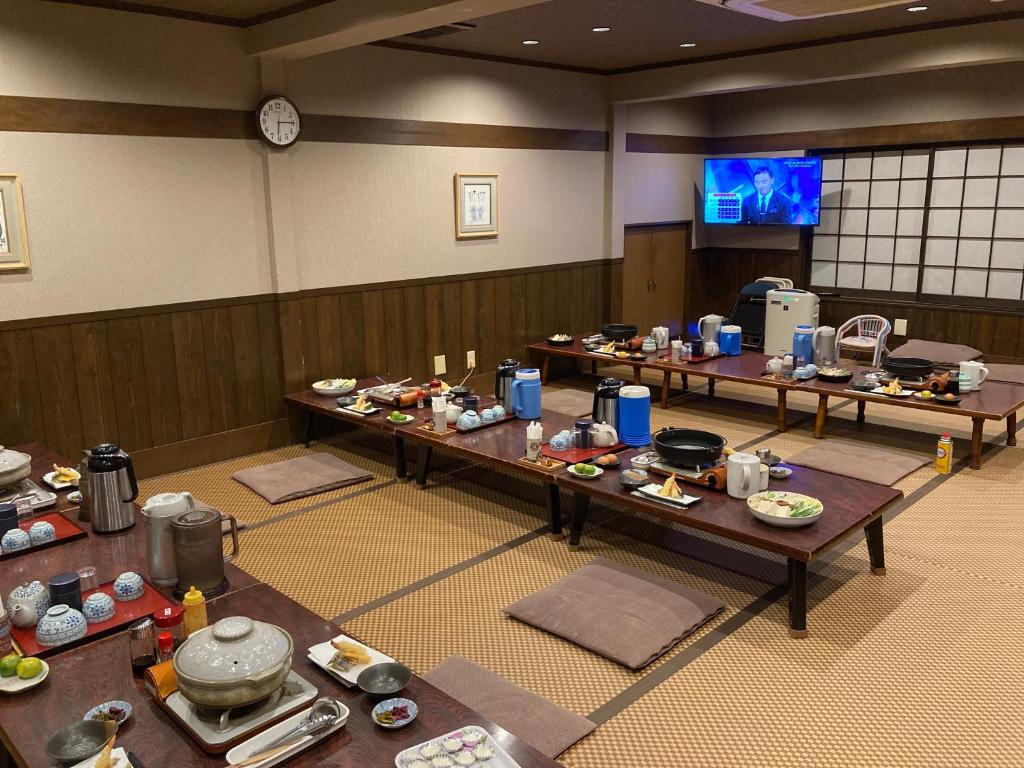 Cette chambre dispose d'une télévision et de tables remplies de nourriture. dans l'établissement Ryoso Chatani, à Kyoto