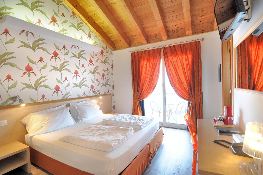 une chambre avec un lit et une fenêtre avec des rideaux orange dans l'établissement Eco Hotel Cleofe, à Caorle