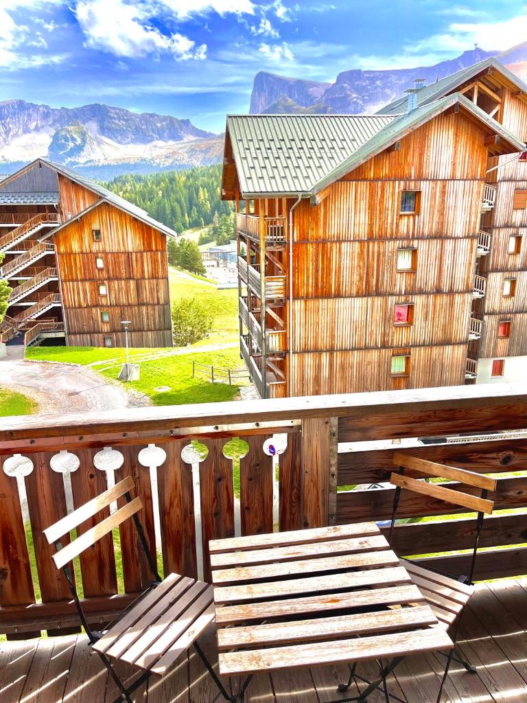 - un banc en bois sur un balcon avec un bâtiment dans l'établissement APPARTEMENT CHALETS DU SUPER D, à Saint-Étienne-en-Dévoluy