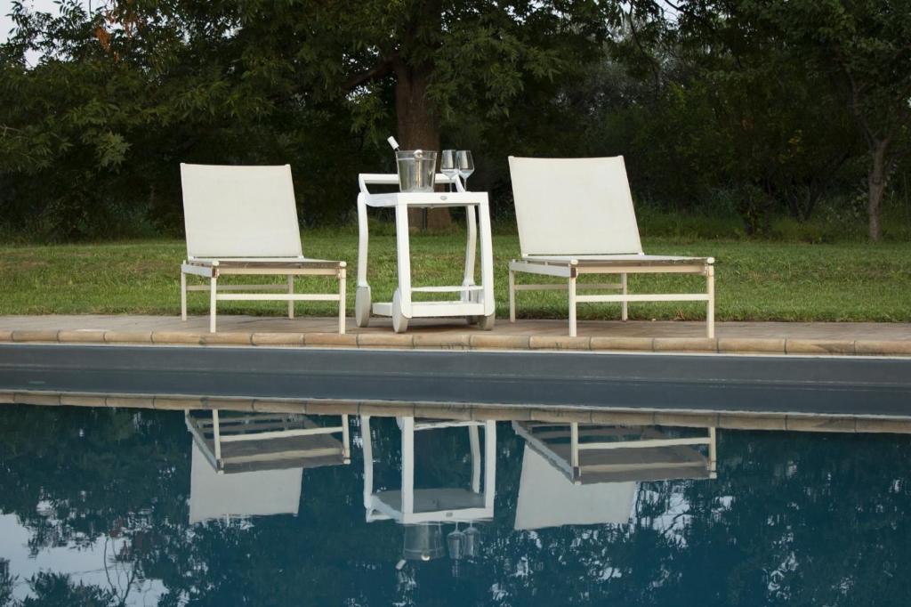 2 chaises et une table à côté d'une piscine d'eau dans l'établissement Villa Tina, à Taormine