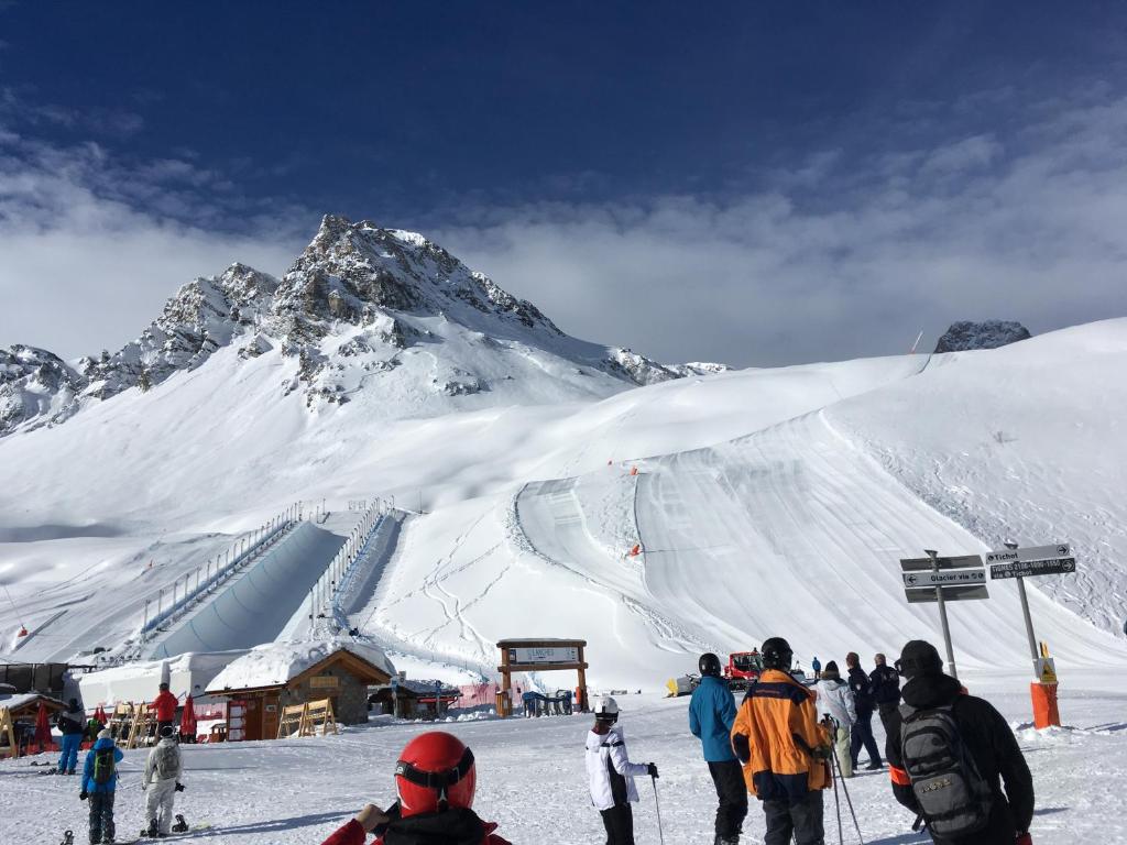 un groupe de personnes debout sur une montagne enneigée dans l'établissement Rond point des pistes 21m pour 4 internet fibre smart TV, à Tignes