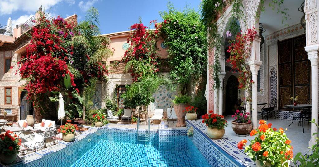 une piscine dans la cour d'un immeuble fleuri dans l'établissement Riad Palais Sebban, à Marrakech