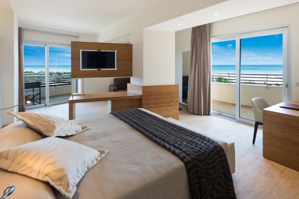 - une chambre avec un grand lit, un bureau et un balcon dans l'établissement Laguna Park Hotel 4Superior, à Bibione
